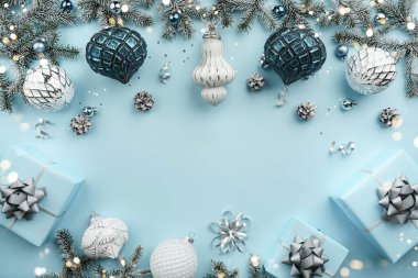 Gümüş Noel köknar dalları, kurdeleli hediye kutuları, beyaz süslemeler, parıltılar ve mavi tatil arka planında konfeti. Noel ve yeni yıl tebrik kartı, kış tatili. Düz konum, üst görünüm, çerçeve