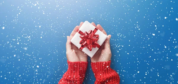 Weibliche Hände Halten Weihnachtsgeschenkschachtel Mit Roter Schleife Auf Hellblauem Hintergrund — Stockfoto