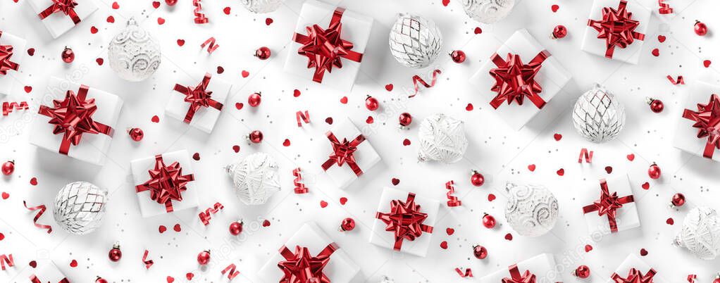 Merry Christmas pattern made of Christmas gift boxes with red bows, silver decoration, confetti on white background. Xmas and New Year holiday banner with bokeh, light, glitter. Flat lay, top view
