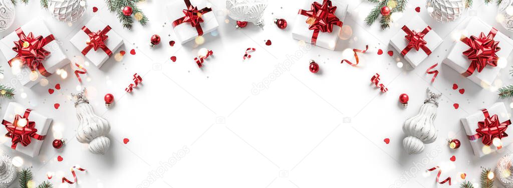 Merry Christmas card made of gift boxes, red and silver decoration, sparkles and confetti on white background. Xmas and New Year holiday, bokeh, light. Flat lay, top view, frame