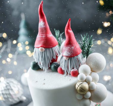 Noel Baba 'nın cüceleriyle süslenmiş Noel pastası, köknar dalları ve parlak arka planda çanlar, çelenk, şeker, bokeh. Noel 'de ya da Yeni Yıl tatilinde, yakın çekim