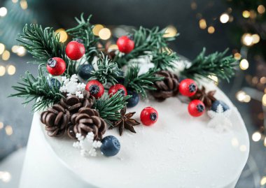 Böğürtlenlerle, kozalaklarla süslenmiş Noel pastası, köknar dalları, parlak arkaplanlı kar taneleri, köknar dalları. Noel 'de ya da Yeni Yıl tatilinde, yakın çekim