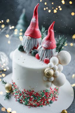 Noel Baba 'nın cüceleriyle süslenmiş Noel pastası, köknar dalları ve parlak arka planda çanlar, çelenk, şeker, bokeh. Noel 'de ya da Yeni Yıl tatilinde, yakın çekim