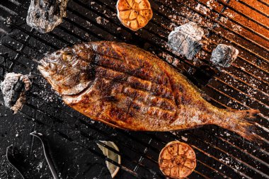 Kömürün üstünde ızgara Dorado balığı, ateş ışığında koyu bir arka plan. Üst görünüm