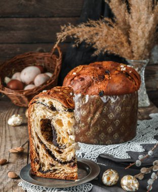 Paskalya pastası dilimi ya da sade ahşap masa üzerindeki ekmek kulich sepeti ve bahar çiçeklerinde renkli paskalya yumurtaları. Mutlu Paskalyalar