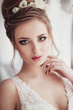 Lüks bir dairede gelinlik içinde güzel bir gelin. Moda makyajı ve saç stili. Genç ve güzel bir gelinin portresi. Düğün için. Stüdyo çekimi.