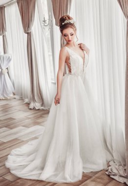 Lüks bir dairede gelinlik içinde güzel bir gelin. Moda makyajı ve saç stili. Genç ve güzel bir gelinin portresi. Düğün için. Stüdyo çekimi.