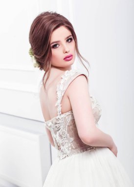 Lüks bir dairede gelinlik içinde güzel bir gelin. Moda makyajı ve saç stili. Genç ve güzel bir gelinin portresi. Düğün için. Stüdyo çekimi.