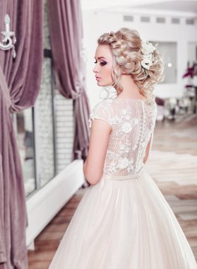 Lüks bir dairede gelinlik içinde güzel bir gelin. Moda makyajı ve saç stili. Genç ve güzel bir gelinin portresi. Düğün için. Stüdyo çekimi.