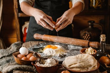 Kadın elleri kırsal ahşap arka planda bir yumurtayı una çevirir. Peynirli, yumurtalı ve otlu ekmek pişirmek. Ev yapımı sağlıklı gıda konsepti