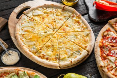 Dört peynirli pizza quattro formaggi, parmesan peyniri, peynir, gouda, mozzarella peyniri ve ahşap tahta üzerinde armut. Vejetaryen pizzası, kapat.