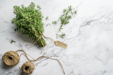 Kekik sürüsü. Açık mermer arka planda bir buket taze kekik ve jüt sicimi. Üst görünüm