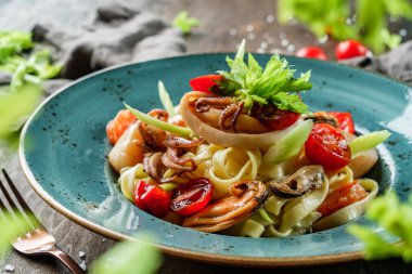 Ahşap zemin üzerinde deniz ürünleri, langoustine, istiridye, mürekkep balığı, midye, karides, kereviz kökü ve limon suyu olan makarna. Sağlıklı yemek, İtalyan mutfağı, yakın çekim.