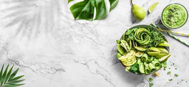 Avokado, kivi, elma, salatalık, armut, mikro yeşillikler hafif mermer arka planda meyve suyu ve tropikal yapraklarla taze yaz salatası. Sağlıklı yemek, temiz yemek, Buda kasesi salatası, üst manzara.