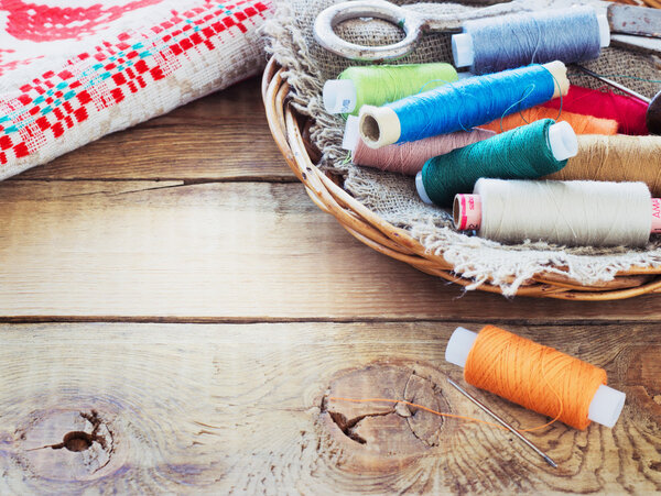 Ножницы, бобины с нитками и иглами, полосатая ткань. Старые швейные инструменты на старом деревянном фоне
.