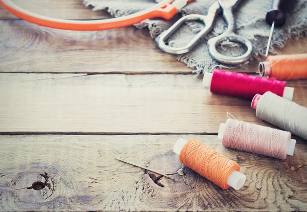 Ciseaux, bobines avec fil et aiguilles, tissu rayé. Vieux outils à coudre sur le vieux fond en bois. Fond Vintage — Photo