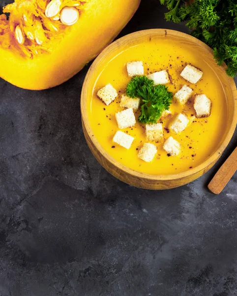 Sopa de calabaza con crema, pan y perejil fresco en un plato rústico de metal sobre fondo negro grunge. Vista superior, espacio de copia Imagen De Stock