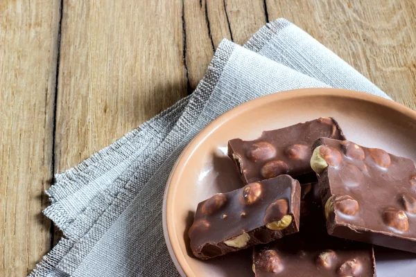 Chocolate, milk, piece, walnuts, hazelnuts, plates, napkins — Stock Photo, Image