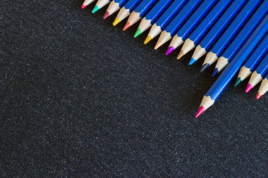 Koyu arkaplanda renkli kalemlerden oluşan bir gökkuşağı..