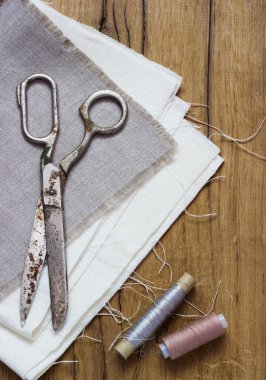 Dikiş takımı. Makas, bobin iplik ve eski ahşap arka plan üzerinde iğne ile