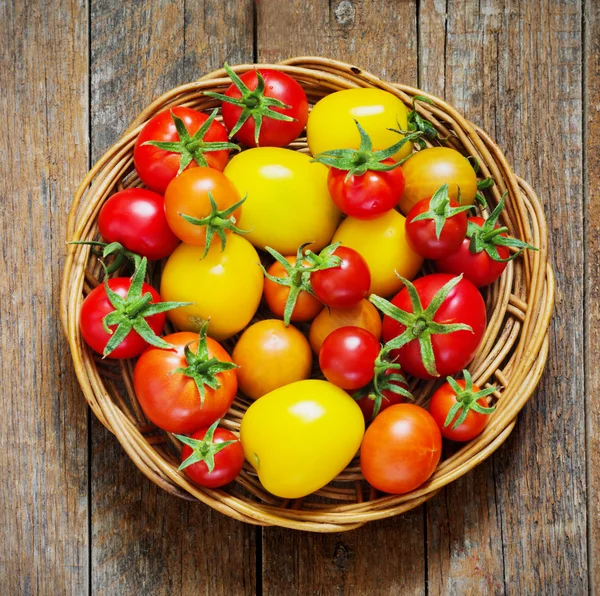 Tomates em cesta de vime em uma mesa de madeira — Fotografia de Stock