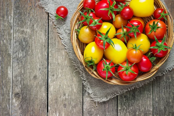 Tomaten in rieten mand op een houten tafel — Stockfoto