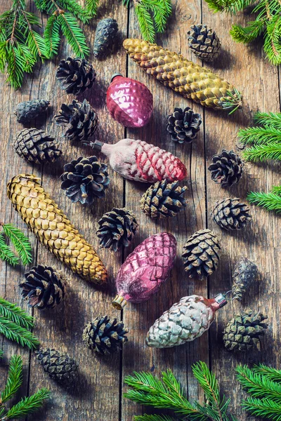 Speelgoed voor de kerstboom en dennenappels op oude houten achtergrond — Stockfoto