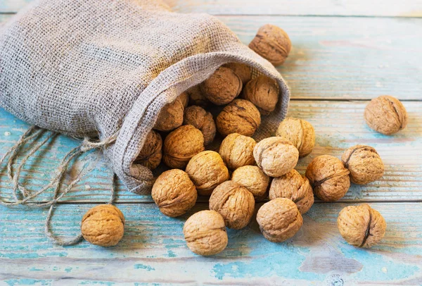 Pile of walnuts in shell inbag on a wooden background