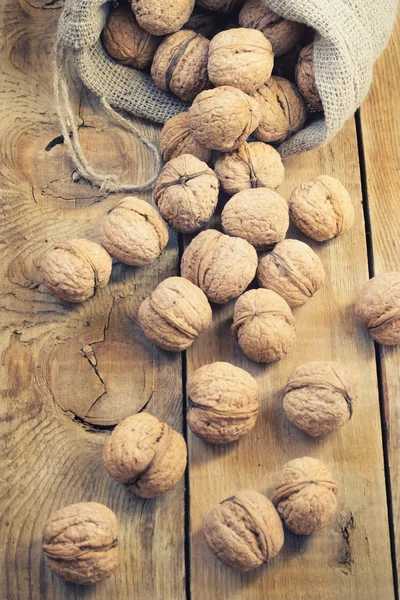 Montón de nueces en bolsa de concha sobre un fondo de madera — Foto de Stock