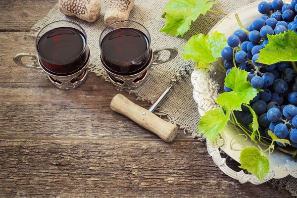 Vino tinto y uvas en ambiente vintage con corchos sobre mesa de madera — Foto de Stock