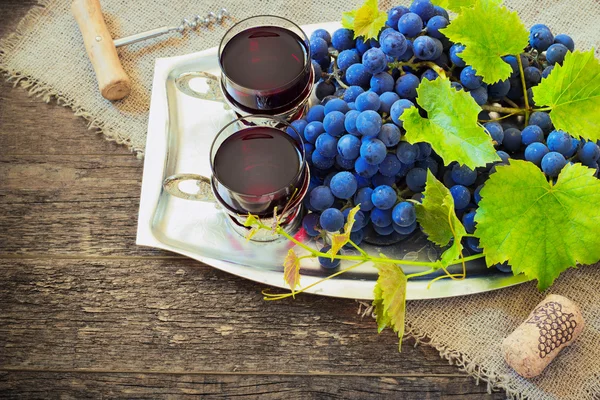 Vino tinto y uvas en ambiente vintage con corchos sobre mesa de madera — Foto de Stock