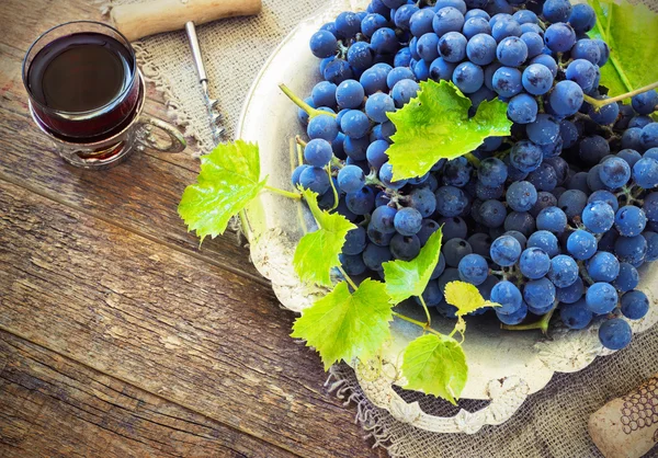 Vino tinto y uvas en ambiente vintage con corchos sobre mesa de madera — Foto de Stock