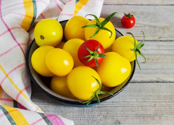 Органічні жовті червоні вишневі помідори з краплями води в синій мисці — стокове фото