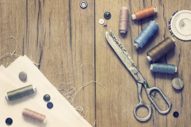Dikiş takımı. Makas, bobin iplik ve eski ahşap arka plan üzerinde iğne ile