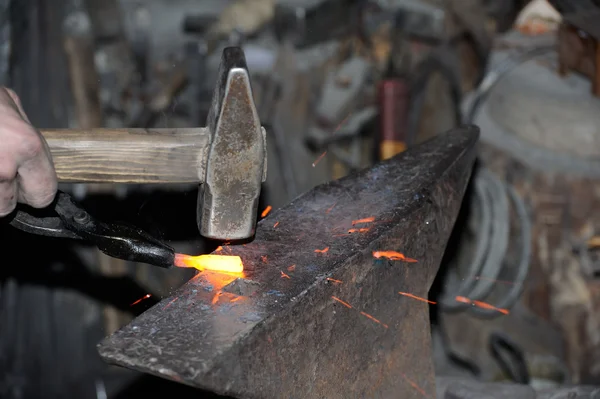 Herrero forja un martillo de metal al rojo vivo — Foto de Stock