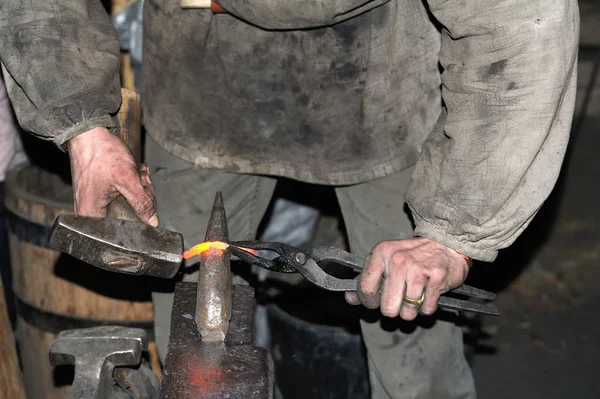 Smid smeedt een gloeiende metalen hamer — Stockfoto