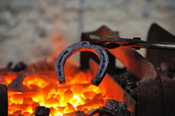 Blacksmith forges a horseshoe — Stock Photo, Image