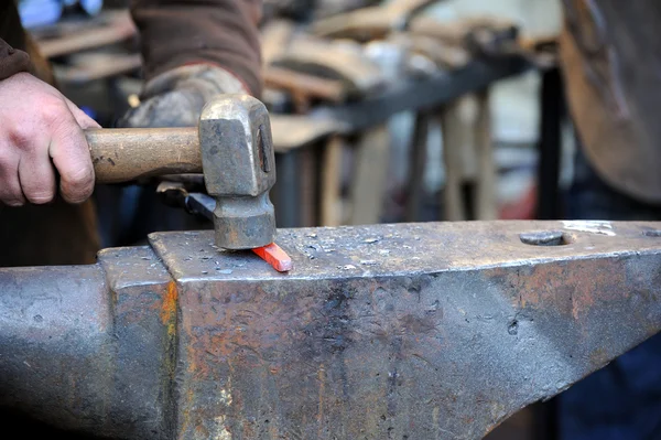 Herrero trabajando metal con martillo en el yunque — Foto de Stock