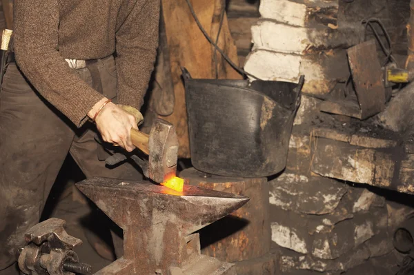 Herrero trabajando en la forja procesa el metal  . — Foto de Stock