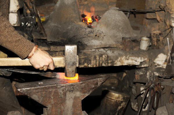 Blacksmith working in the forge processes the metal .