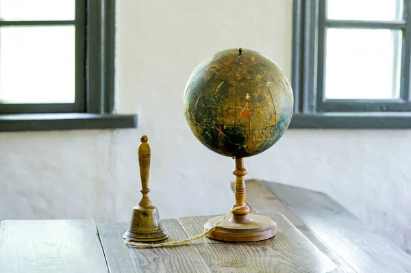 An old globe lying on a table  against the background class room. Retro style. Science, education, travel, vintage background. Education history and geography team.