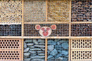 Yeşil bir çalılıktaki böcek oteli arılara ve diğer böceklere koruma sağlar. 