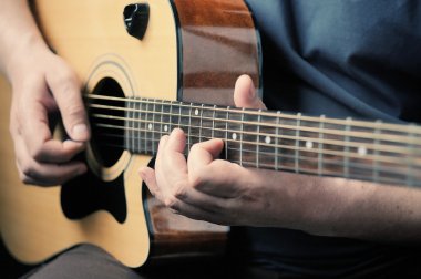Adam akustik gitar çalıyor. 