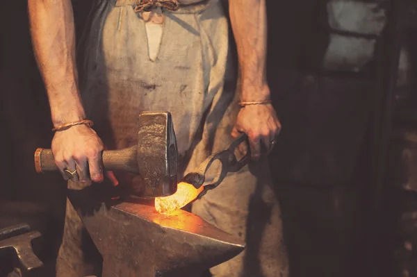 Кузнец обрабатывающий металл с молотком — стоковое фото