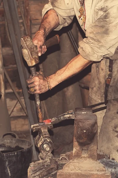 Fabbro lavorazione metallo con martello — Foto Stock