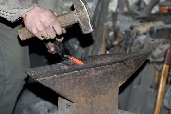 Smid smeedt een gloeiende metalen hamer — Stockfoto