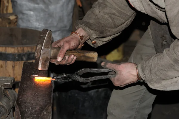 Smid smeedt een gloeiende metalen hamer — Stockfoto