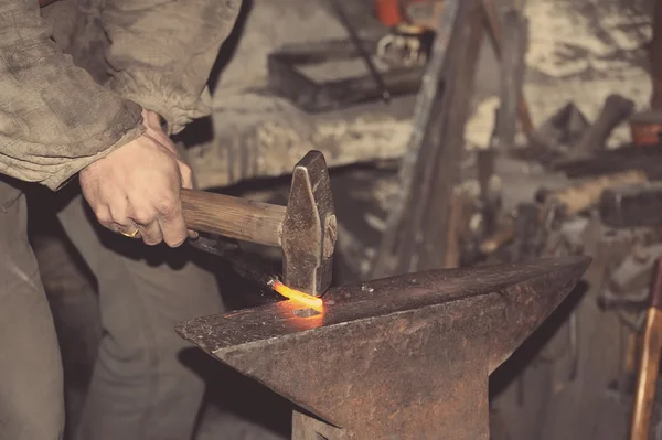 Smid smeedt een gloeiende metalen hamer — Stockfoto