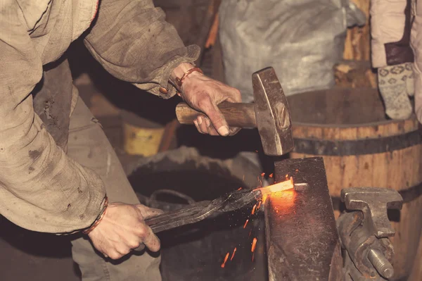 Smid smeedt een gloeiende metalen hamer — Stockfoto
