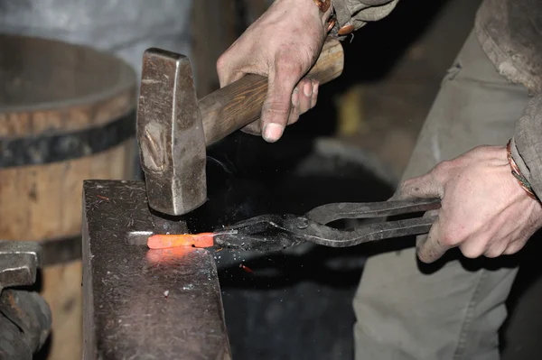 Smid smeedt een gloeiende metalen hamer — Stockfoto